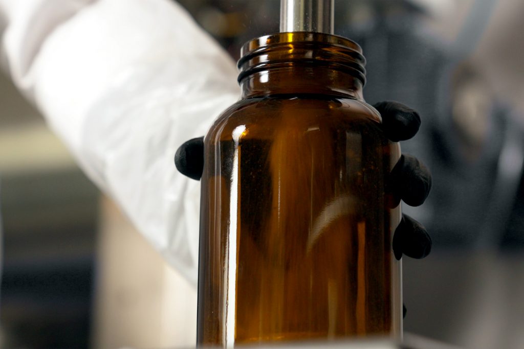 Braunglasflasche wird bei der Lohnabfüllung von Nahrungsergänzungsmitteln präzise befüllt